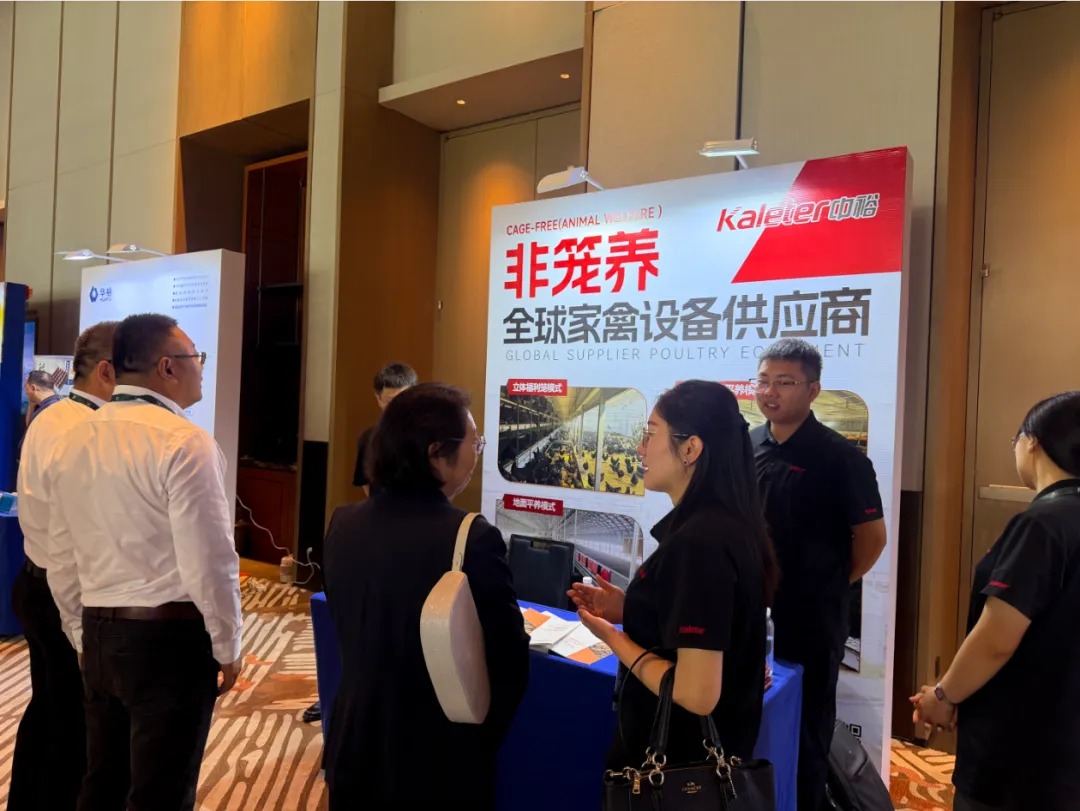 Kaleter team members speaking with visitors at the Kaleter booth, with a cage-free equipment display banner