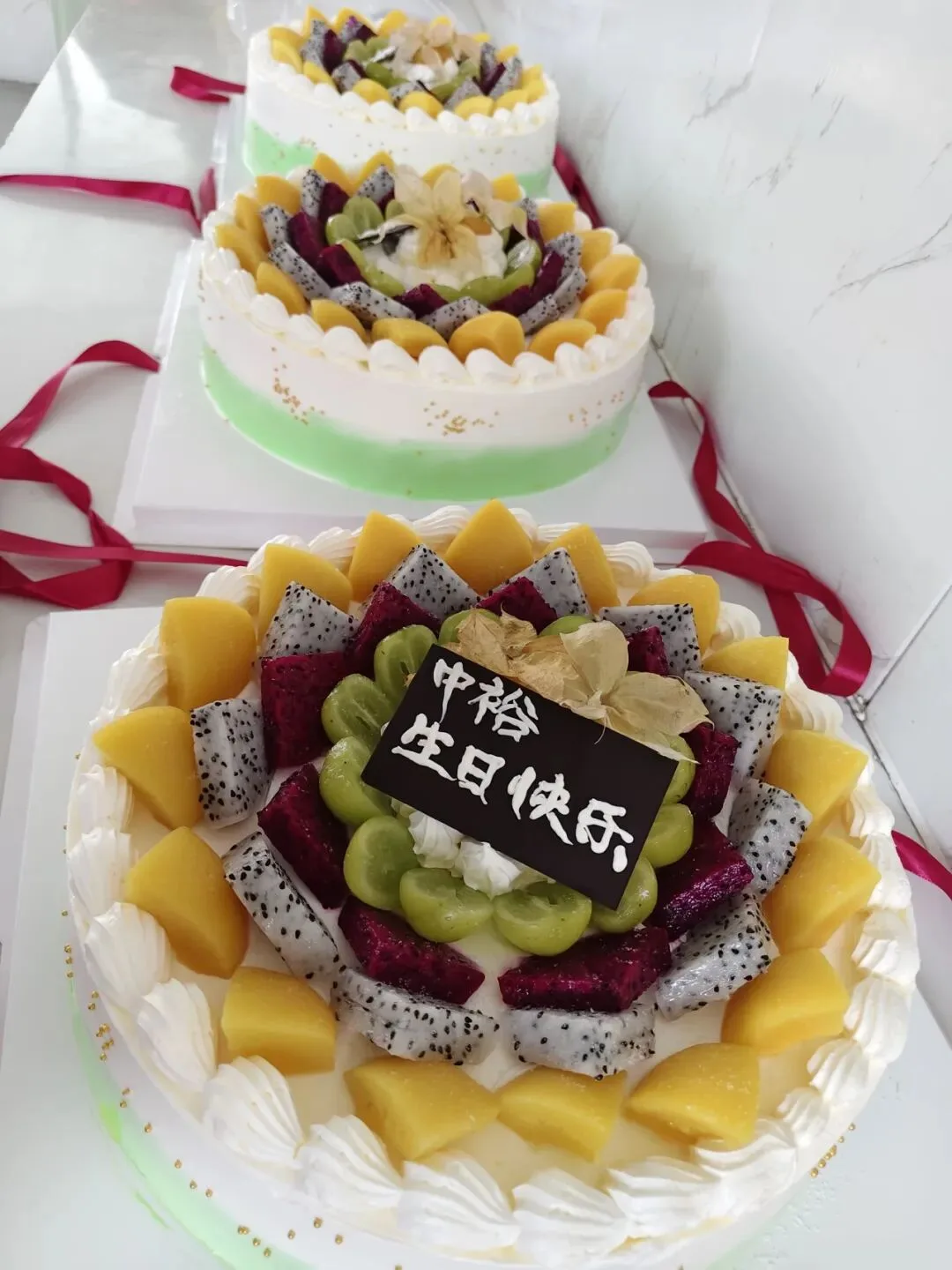 Birthday cakes topped with fresh fruit set out on the table