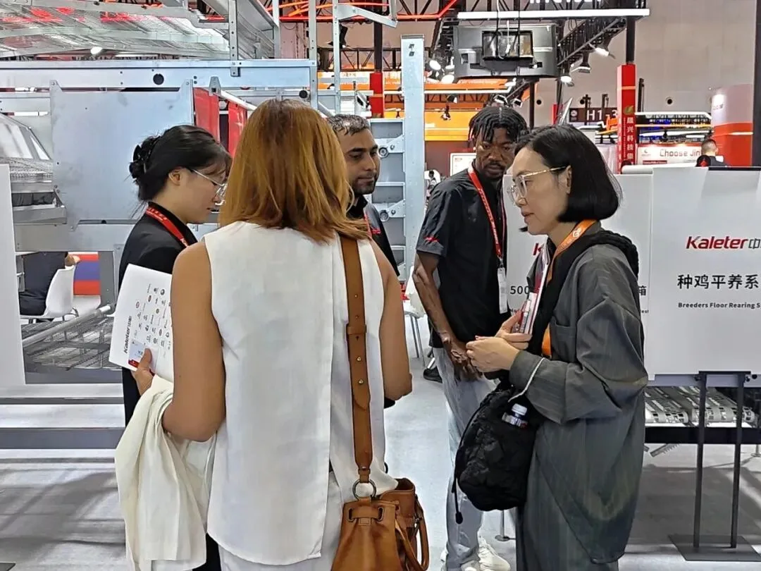 Kaleter staff talking with visitors in front of the breeder floor rearing system display